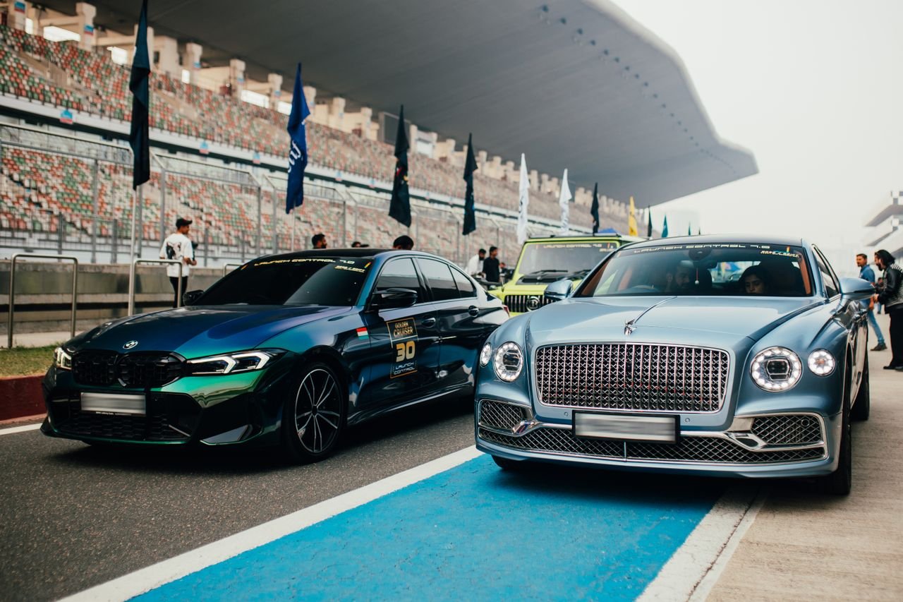 our-mission Elegant lineup of luxury cars at a racing event in Greater Noida, India, showcasing Bentley and BMW models.