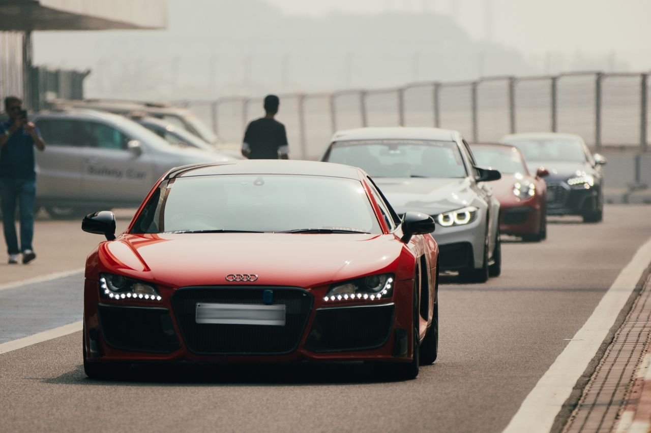 A striking red Audi R8 leads a lineup on a race track in Greater Noida, India.